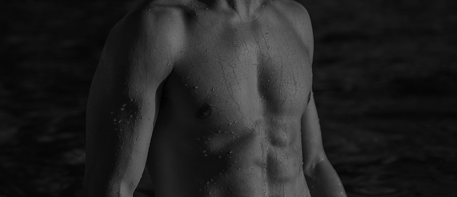Close-up of a wet, toned male torso.