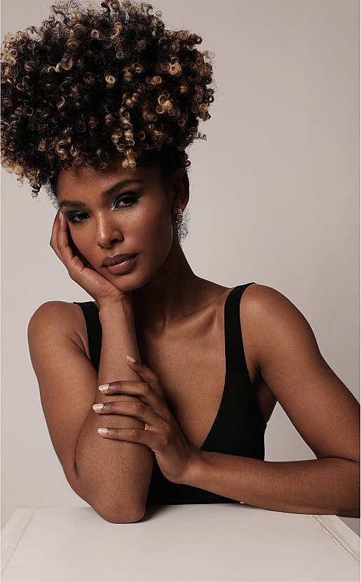 Woman with curly hair, natural makeup posing elegantly.