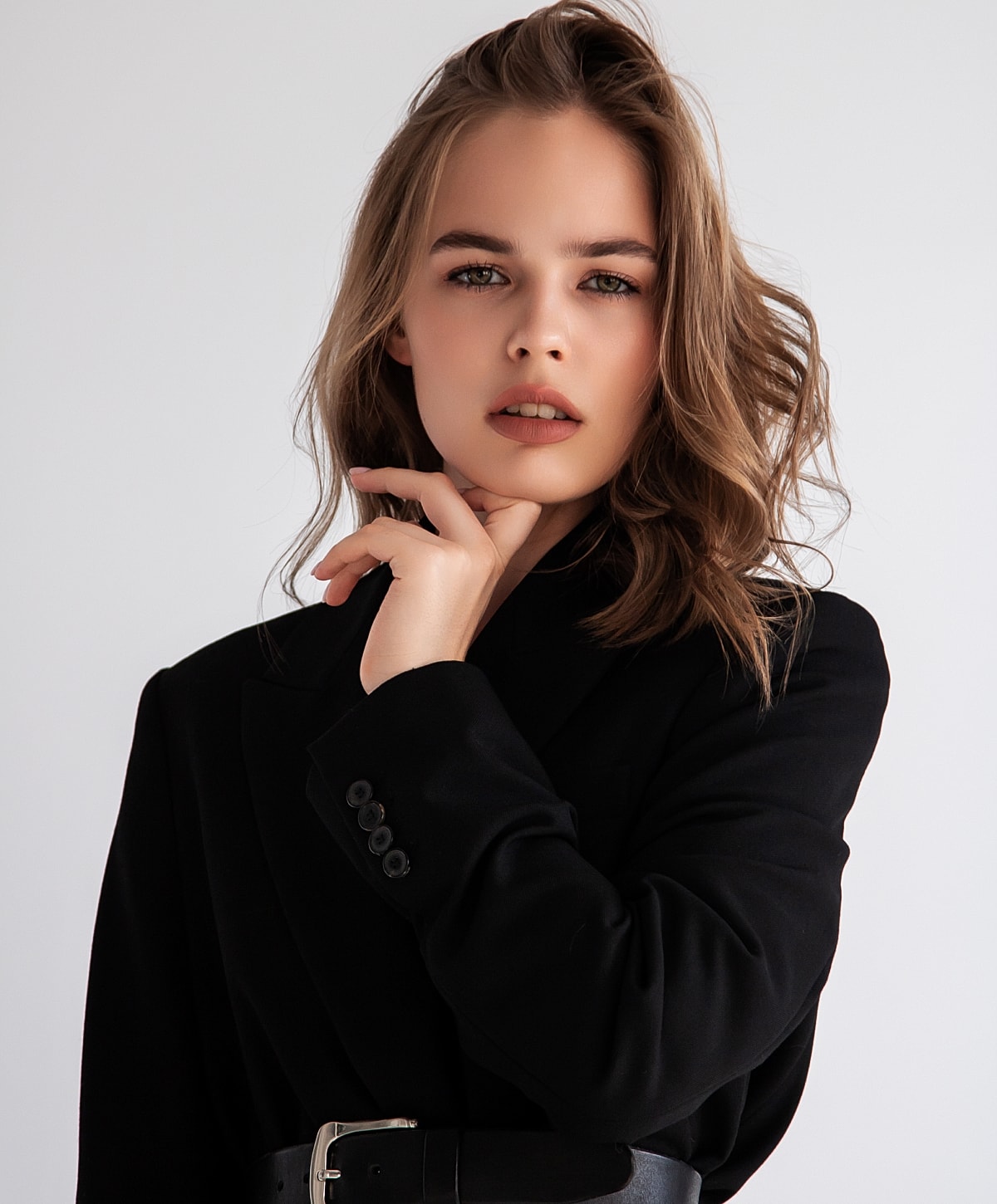 Woman in black blazer, posing thoughtfully.