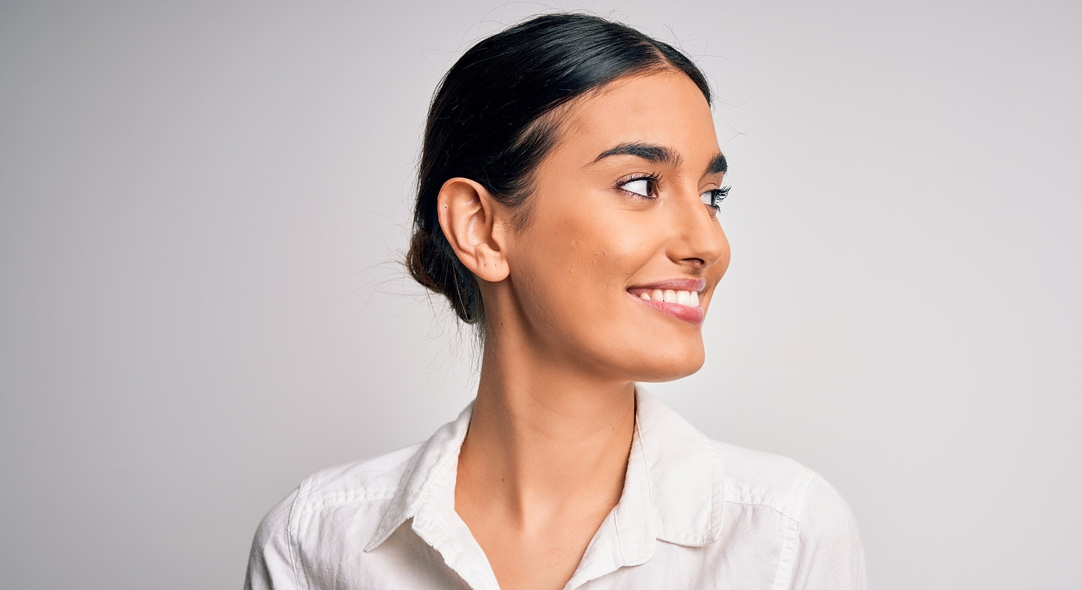 Smiling young woman with dark hair, profile view.