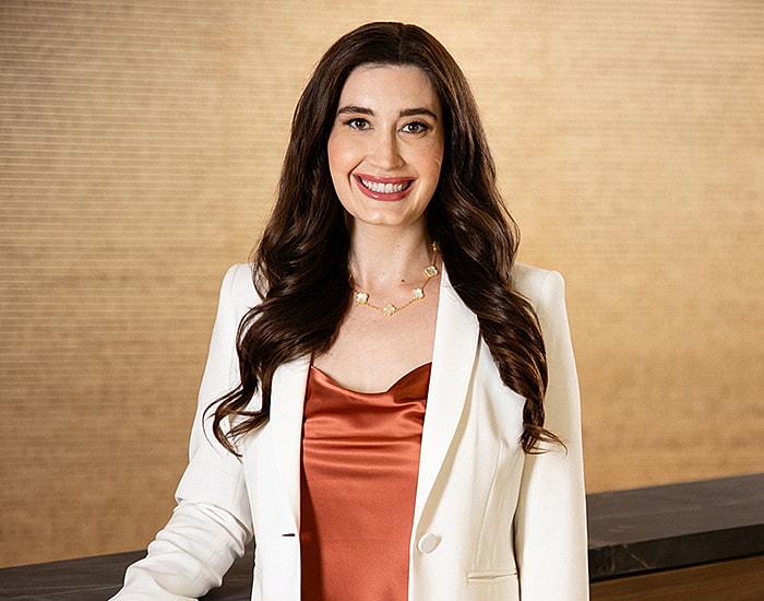 Woman smiling in professional attire, indoor setting.